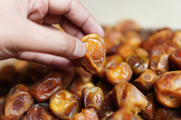 Close-up showcases the texture of dates, emphasizing their natural sweetness and rich color. A hand selects a perfectly ripe date, highlighting the quality of this healthy snack food.