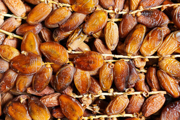 A close-up captures the luscious texture and rich color of clustered dates. The dates glisten invitingly, showcasing the natural sweetness and chewy consistency of the popular fruit.