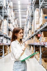 Focused on her task, a young mixed race woman holding clipboard meticulously updates inventory...