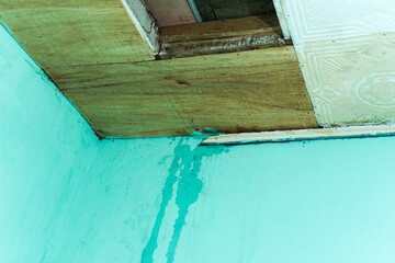 A damaged ceiling shows water leaks running down a blue wall, illustrating home repair and maintenance challenges, signifying potential damage and the need for immediate renovation.