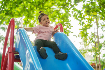 happy toddler baby girl sliding and playing at playground