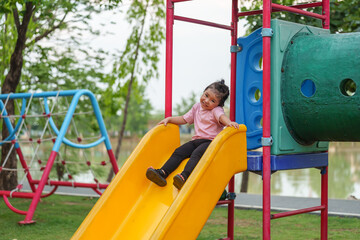 happy toddler baby girl sliding and playing at playground