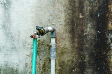 A close-up showcases an old water faucet and pipes against a weathered wall, featuring an outdoor plumbing fixture with visible wear and aged textures. The image focuses on rustic utility.