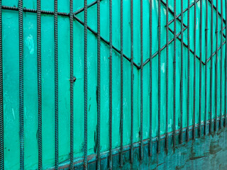 Green backdrop with a textured rebar pattern creates a dynamic industrial aesthetic. The weathered...