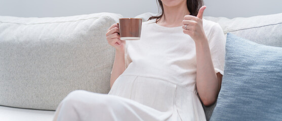 マグカップで飲み物を飲む妊婦