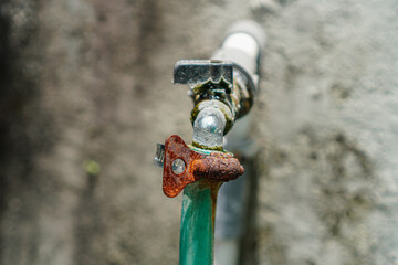 A close-up captures the weathered texture of a garden hose and faucet, adorned with rust and age. The corroded metal and verdigris evoke themes of decay, time's passage, and outdoor usage.