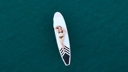 A young man is enjoying his ocean adventure aboard a yacht and surfboard