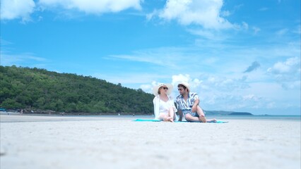 Fototapeta premium Young couple on vacation on a white sandy beach, clear sky and sea