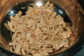 Shredded chicken meat in a metal bowl, perfect for various culinary applications. Ready for sandwiches, salads, or tasty meals. Neutral color palette for versatile use and adaptability.
