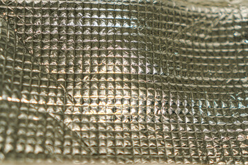 Abstract close-up of a shiny, metallic surface with a textured, geometric pattern. The material's...