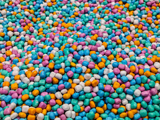 A vibrant and dense scattering of pastel candy pieces creates a textured and eye-catching...
