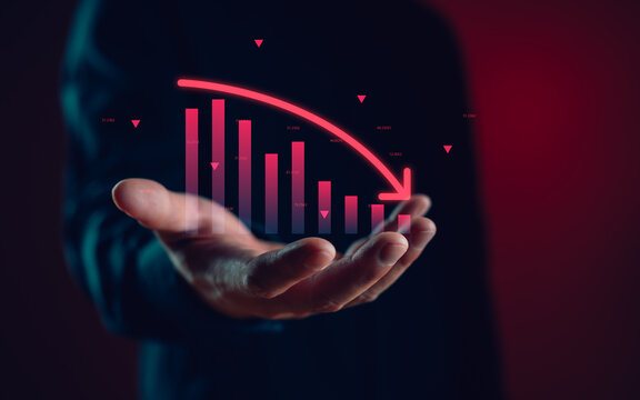 Stock market crash concept with a hand holding a declining bar chart and red arrow, representing financial loss, recession, poor economy, investment failure, and profit decrease.