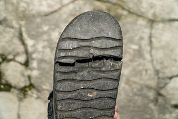 Close-up of a worn-out sandal sole reveals cracks and weathering, symbolizing time, wear, and...