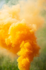 Bright Orange Smoke Rising from Ground Level. Smoke Bomb with Green Grass Background.