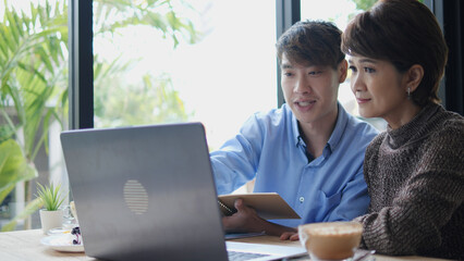 Mentorship and teamwork concept with two people focused on laptop in a cozy café, sharing ideas over coffee, representing education, digital communication, and intergenerational cooperation.