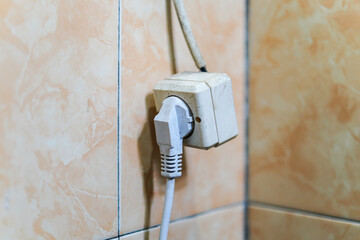 A close-up shot highlights an electrical outlet and plug against a marble tiled backdrop. The...