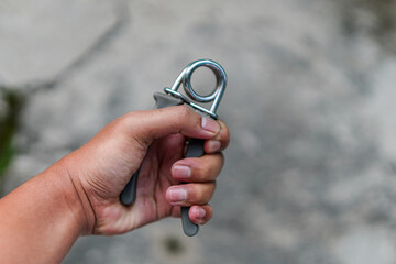 A hand grips a hand strengthener, showcasing wrist and forearm fitness. Ideal for health and exercise marketing. The exercise equipment is a versatile tool for building strength and endurance.