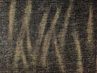 Close-up of dark denim fabric with worn vertical texture.