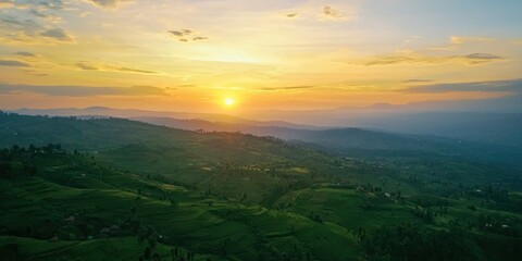 A high-altitude viewpoint showing the sun setting over rolling hills and distant valleys