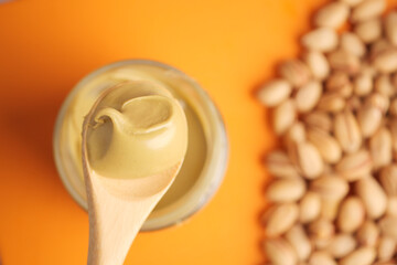 Creamy pistachios nut butter spread with wooden spoon and nuts nearby