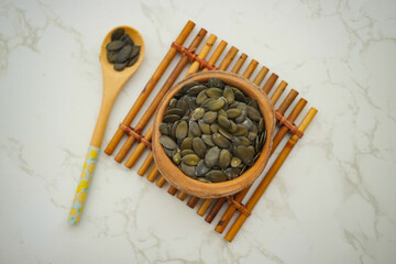 Healthy pumpkin seeds in a wooden bowl on a mat