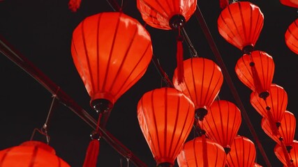 Glowing red lanterns softly swinging, casting warm light against shadowy background, highlighting festive asian cultural celebration - Powered by Adobe