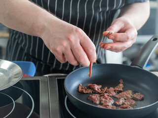 The chef fries veal in a frying pan. 