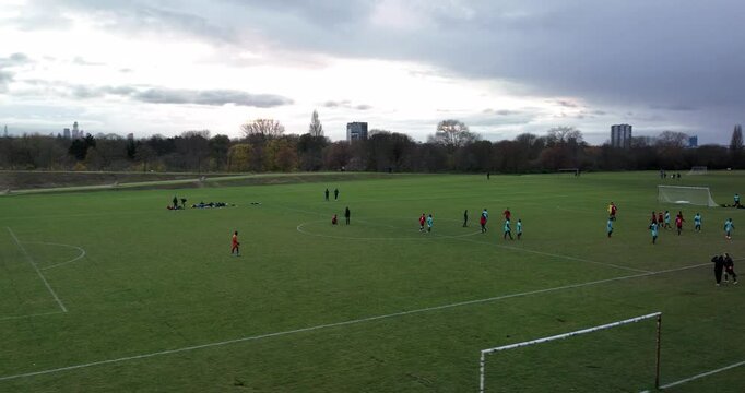 /People in sports jerseys walking on green lawn. Slide and pan shot of players after football match. London, UK