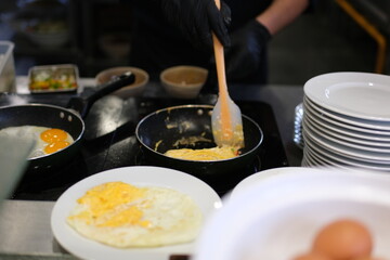 Frying eggs stovetop hand cracks an egg into a frying pan on a stovetop. This close-up shot captures the beginning stages of cooking and the preparation of a simple meal