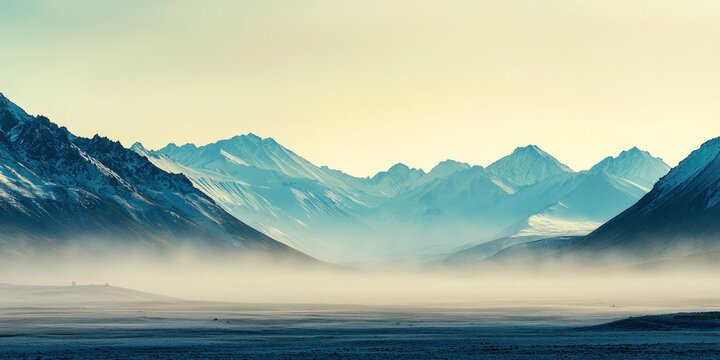 A serene valley covered in morning mist, with distant mountain peaks barely visible