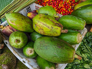 A vibrant collection of freshly harvested tropical fruits and vegetables arranged in a basket, showcasing the colors and textures of nature's bounty, ideal for healthy lifestyle concepts.