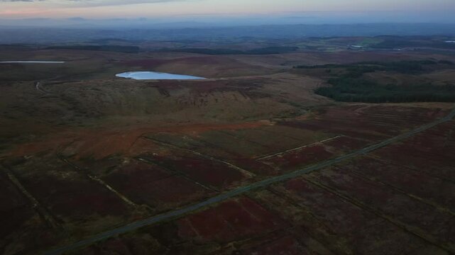 Bragan, County Monaghan, Ireland, September 2022. Drone panoramic aerial overview of bog textures surrounding Lake Menish with textured sloping hills divided into parcels, soft gradient horizon.