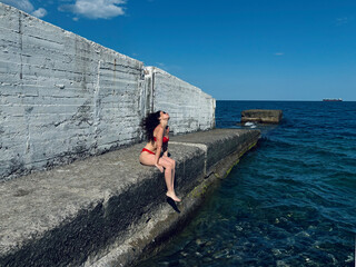 The breakwater of the sea is a lonely bather. The girl in the red bikini.