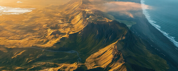 Aerial view of dramatic mountain range meeting the ocean at sunrise