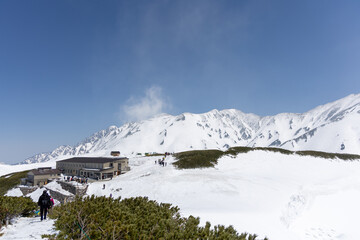 4月の春、青空の下に堂々と広がる真っ白な立山連峰の雄大な雪景色。季節の移ろいを感じる静寂の風景。
