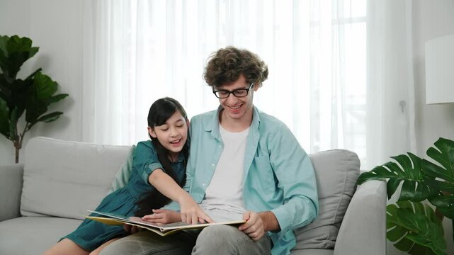 Happy dad telling story and moving gesture while funny schoolgirl pointing at story book. Student listen and enjoy talking about fairytail while looking parent. Family recreation concept. Pedagogy.