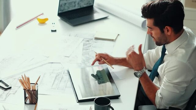 Architect engineer using laptop planning house design at office while sitting at meeting table with blueprint and equipment scatter around.Skilled civil engineer working at blueprint. Alimentation.