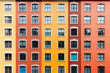 Colorful building facade featuring rows of windows and vibrant hues, creating a striking architectural pattern. Abstract.