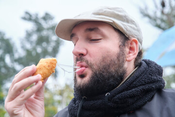 Young hisoanic man enjoying eating a freshly made Argentinean ham and cheese empanada outdoors.