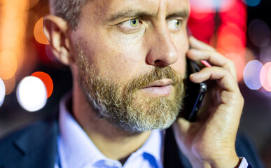 Businessman talk on phone at night city. Rich man in suit with phone in city. Businessman using...