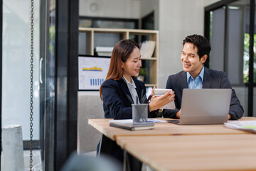 Team of Asian business people point to graphs and charts to analyze market data, balance sheet, account, net profit to plan new sales strategies to increase production capacity.
