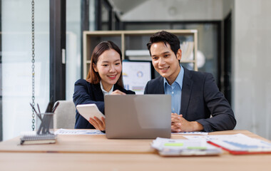 Team of Asian business people point to graphs and charts to analyze market data, balance sheet, account, net profit to plan new sales strategies to increase production capacity.
