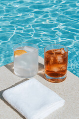 Refreshing poolside drinks beckon. Ice-cold beverages next to the pool create a relaxing summer vibe. Cool off with a drink near shimmering water.