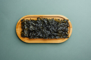 roasted seaweed snack on wooden tray over green background