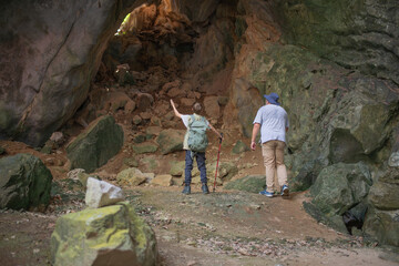 Tourist trekking with backpack and using a walking stick, gesturing forward suggesting of adventure or discovery in cave mysterious and ancient outdoor adventure concept.
