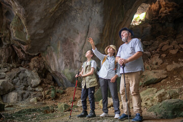 Tourist trekking with backpack and using a walking stick, gesturing forward suggesting of adventure or discovery in cave mysterious and ancient outdoor adventure concept.