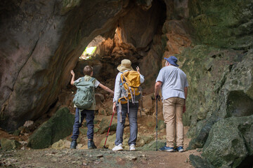 Tourist trekking with backpack and using a walking stick, gesturing forward suggesting of adventure or discovery in cave mysterious and ancient outdoor adventure concept.
