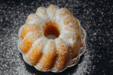 Bundt cake with powdered sugar on black background