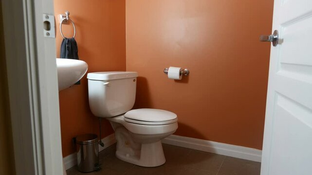 Smooth slider shot of the interior of a small domestic home bathroom, washroom. Toilet and sink. Zooming out through the doorway.