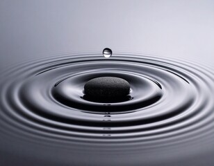 A silver droplet hovers above smooth, slate-gray rings